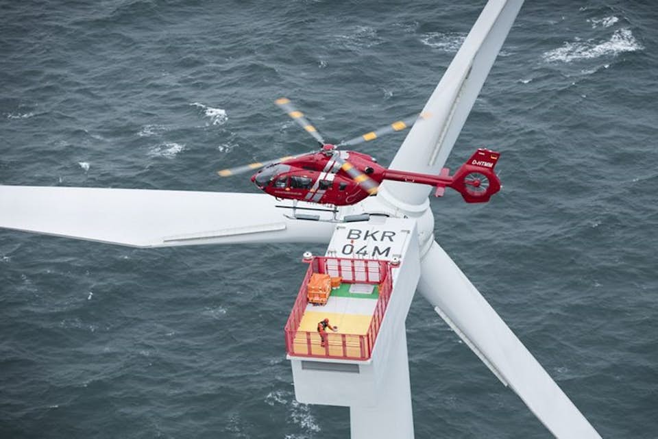 helicopter hovers above offshore wind turbine