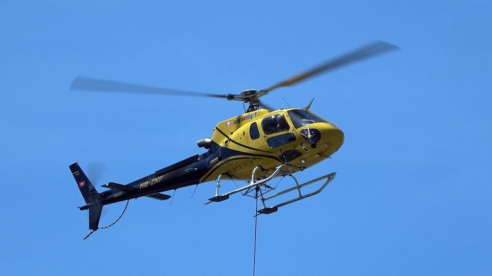 Yellow construction helicopter against blue sky
